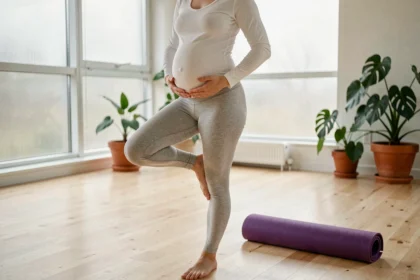 Femme enceinte pratiquant une pose de yoga prénatal douce dans un studio minimaliste en bois clair